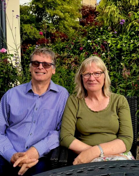 Fergus and Hilary Law seated together in a garden